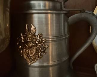 Pewter lidded tankard with brass crest emblem and thumb latch