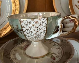 Footed lusterware teacup and saucer with hand painted floral gilt trim