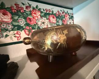 Brass engraved decanter with Aztec sun motif on wall shelf
