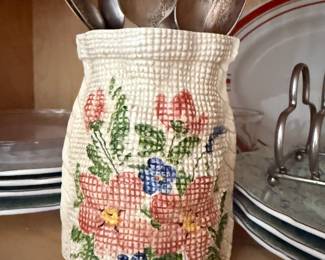 Textured ceramic vase with hand-painted floral design, holding vintage spoons