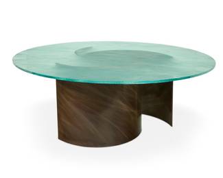 2321 A Contemporary sculptural dining table Late 20th/early 21st century The tempered round glass top with frosted upper surface, raised on three semi-cylindrical metal panels, each with a brushed bronze-toned finish, sculpted by Greg Higgins (20th/21st Century) 4 pieces Height of each arc 28 in., width 32 1/2 in., depth 12 1/4 in.; height of glass 3/4 in., diameter 71 3/4 in. Estimate: $800 - $1,200