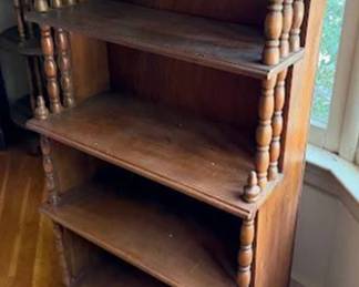 Wooden bookcase featuring four shelves and turned spindle side details. Measures 46 inches high, 25 inches wide, and 9 inches deep. The finish shows signs of surface wear. Simple classic design, suitable for storage or display.