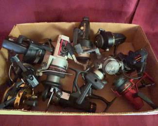 Fishing reels, including Daiwa, Shakespare, Garcia, and other brands. Both spinning and casting reel types present. Reels show visible surface wear, some oxidation, and use.
