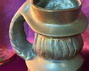 Collection includes a pair of brass candle holders, a brass figural jug, a leaf-shaped leaf tray signed 'J.B. 1973 Susan Bag', a 'Thomas Jefferson Cipher' Monticello brass trivet, and a 'James Madison Cipher' NY Gibbs brass trivet. 