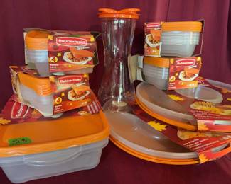Multiple Rubbermaid TakeAlongs food storage containers with orange lids, compartment trays, and a clear plastic beverage pitcher.