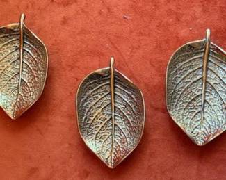 Virginia Metalcrafters solid brass dishes in leaf and flower forms. Includes three hydrangea leaf dishes, three dogwood leaf dishes, and one dogwood flower. Maker's mark on each piece. Suitable as decorative or catchall dishes.