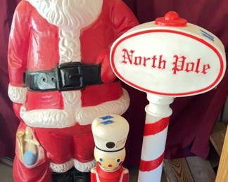 60-inch tall plastic Santa Claus figure, a 46-inch tall North Pole sign with red and white pole, and a 30-inch tall toy soldier figure.