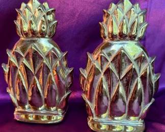 Newport NB-2 brass pineapple bookends, a pineapple motif trivet marked 'Copyright 1976' and '10-46', brass candlesticks, and a wreath holder with decorative pineapple accent. The bookends have Newport signature marks and the trivet is marked with maker details and year. 