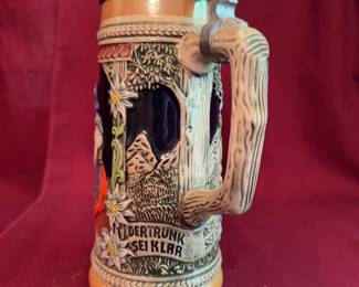 Krosnoerney beer stein, made in Germany, features hand-painted ceramic with traditional Alpine scenes and German inscriptions, detailed handle, and a hinged pewter lid. Height is 9 inches. Marked on base.