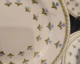 Crescent China England dinner and side plates featuring a green leaf and blue flower pattern with gold accents. Several plates show visible cracks and signs of wear. Makers mark present on the underside.