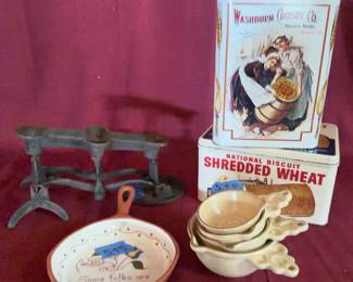 Metal advertising tins for Washburn Crosby Co. Gold Medal Flour and National Biscuit Shredded Wheat, a cast iron balance scale, a ceramic frying pan marked "Some folks are wonderful nice," and four ceramic measuring cups marked "1/4 cup." 