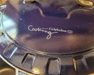 Calphalon enameled cast iron Dutch ovens in blue. Includes Dutch oven with lid and one smaller Dutch oven. Some enamel wear is visible. Both pieces feature the "Cooking with Calphalon" branding.