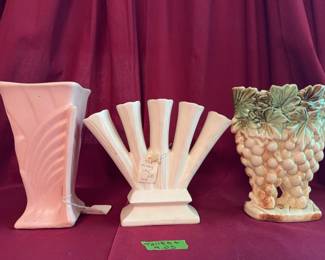Ceramic vases, including McCoy USA markings. Fan vase with a grapevine motif, a pink art deco-style vase, and a leaf and grape cluster motif vase. Visible crazing, surface wear, and some cracks are present.