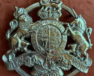 Brass candlesticks, two monogrammed brass trivets, a 1963 King's Arms Tavern Williamsburg plaque, an eagle bottle opener marked 24-81, and a heraldic plaque with a lion and unicorn crest. All pieces are brass.