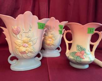 Hull Pottery USA ceramic pieces, including two vases and one handled pitcher, each in pastel pink and blue with raised floral designs. Hull Art marked on bases with shape numbers.