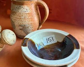 Studio pottery pieces: covered casseroles with handles, two small bowls, a floral-motif cylindrical vessel, and two handled pitchers. Some pieces are artist signed on the base. Various earth-tone glazes throughout the group. 