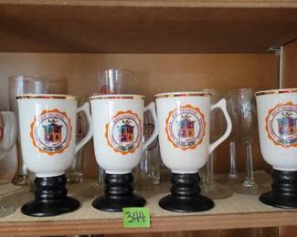 Ceramic mugs with gold trim, wine glasses, and tall glasses, each featuring the Virginia Polytechnic Institute and State University crest.