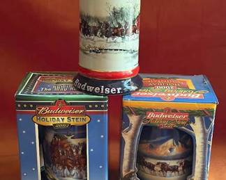 Budweiser holiday stein mugs including 2000 and 2002 editions in original boxes and one open stein with Clydesdale imagery. Each features winter scenes and Anheuser-Busch branding. Collectible items in ceramic. 