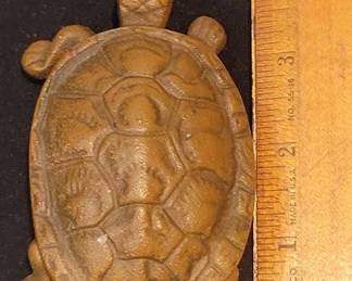 Cast iron trinket box in the form of a turtle, featuring a hinged shell lid. Measures approximately 4 inches long. The finish is consistent with a bronzed or painted surface. No distinct maker's mark visible. Shows some slight wear on the surface.
