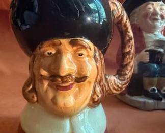 English-made character jug and Toby mugs. Includes Olde Staffordshire and Sylvac, all hand-painted. Makers marked "Made in England." Characters include Gaffer, Toby, Beefeater, and two others. Ceramic construction.