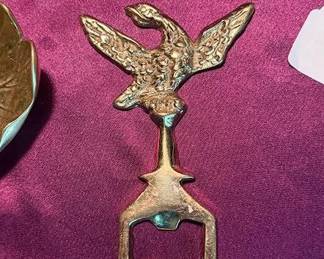 Brass candlesticks, a cast brass bear figurine, a leaf-shaped brass dish, a brass bottle opener marked 'WM', and a British royal coat of arms wall plaque.