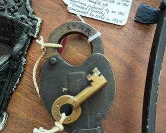Iron trivets, a Chesapeake & Western Railroad padlock with key, a cast iron "Venus & Cupid" match holder, and a cast iron reproduction trivet from Museum of Fine Arts Boston. 