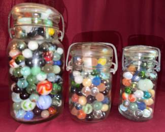 Glass jars each filled with a variety of colorful glass marbles.
