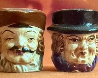 Figural ceramic salt and pepper shakers depicting male heads with hats, with stoppers on the base. Marked "Made in Japan." Each shaker features a handle and hand-painted details.