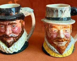 Hand-painted ceramic character mugs by Lancaster & Sandland Ltd, England. Designs depict Raleigh and Drake, marked and designed by J.M. Sandland. Each mug features detailed faces and period costumes.