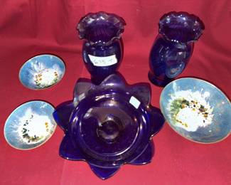 Cobalt blue glass vases with ruffled edges, a cobalt blue flowered bowl, and blue enamel decorated dishes with abstract floral motifs. Visible signature on one dish reads "Saslawi."
