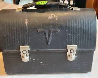 Metal lunch box made by Thermos, featuring a ribbed exterior, dual latch closure, and a sturdy handle. The interior is painted white and shows typical wear consistent with age. Made by American Thermos Products, Norwich, Connecticut, USA.