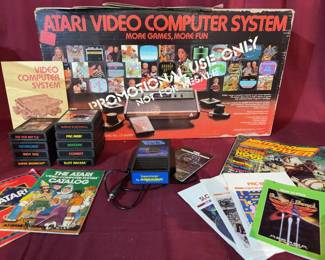 Atari 2600 Video Computer System model CX-2600A, Taiwan, in original box marked promotional use only. Includes console, two joystick controllers, two paddle controllers, Supercharger, power supply, nine game cartridges, manuals, catalogs, and Nintendo Power magazine. Condition and function not tested.