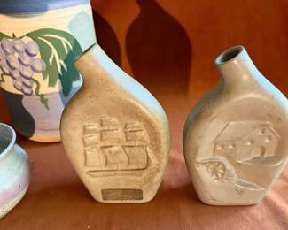 Grape motif vase signed "CM," two jugs with raised fruit, ship, and mill designs, two 'Produce Partners' speckled bowls marked USA with a maple leaf, a green glazed bowl marked 'Byronto Pottery' 2003, and a small speckled bowl.