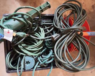 Green heavy-duty extension cords and one orange plastic extension cord reel.