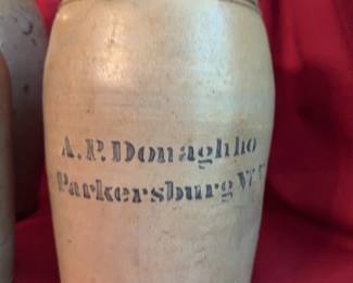 Three stoneware containers including a handled jug (12.5" tall), a wide-mouth jar with impressed seal (9.5" tall), and a crock marked A.P. Donaghho Parkersburg, W.Va. (9.5" tall). 