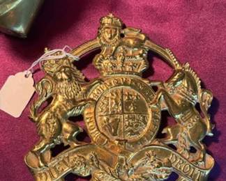 Brass candlesticks, a cast brass bear figurine, a leaf-shaped brass dish, a brass bottle opener marked 'WM', and a British royal coat of arms wall plaque.