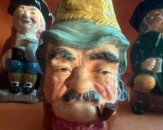 English-made character jug and Toby mugs. Includes Olde Staffordshire and Sylvac, all hand-painted. Makers marked "Made in England." Characters include Gaffer, Toby, Beefeater, and two others. Ceramic construction.