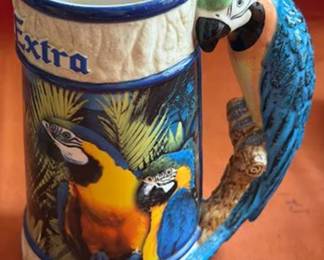 Decorative beer steins featuring brands such as Miller, Corona Extra, and Budweiser with designs including 1804 Explorer, parrots, and a baseball scene. Also includes two Old Milwaukee beer tap handles and one Schlitz tap handle.