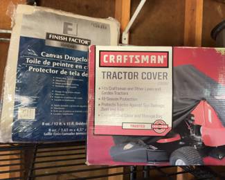 One Craftsman tractor cover in original packaging, featuring all-season protection with elastic shock cord, plus one Finish Factor 8 oz. cotton canvas dropcloth, size 12 ft x 15 ft, still sealed. Packaging shows minor shelf wear.
