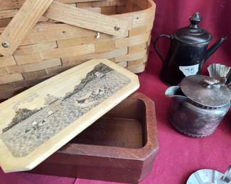 Woven wood basket with handles, a lidded wooden box with scrimshaw-style etched nautical lid, two black metal teapots or creamers, a set of six clear glass candle bobeches, two metal taper candle holders, and four small fluted metal candle holders. Wear and tarnish noted on metalware. Box features maritime scene.