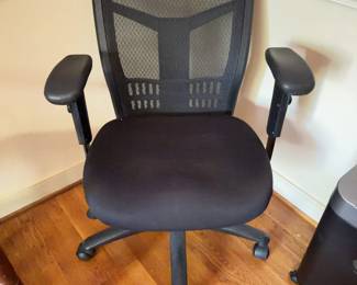 Office chair featuring a black mesh backrest, cushioned fabric seat, and adjustable armrests. Equipped with a five-wheel plastic base and various height and tilt adjustment levers.