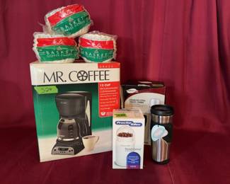 Mr. Coffee 12-cup programmable coffee maker model DRX23, a Proctor Silex Fresh Grind coffee grinder, packs of Melitta basket coffee filters, a ThermoServe stainless steel travel combo pack, and a Raya stainless steel travel mug.