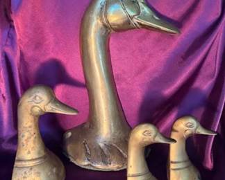 Duckhead sculptures crafted from brass, featuring three smaller and one larger piece. Each sculpture is detailed with incised lines to depict the facial features and neck markings of ducks. 
