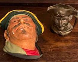 Painted pirate head wall plaque and a brass pirate-shaped mug. The mug is marked "Made in India." Both items depict pirate characters with hats and mustaches.