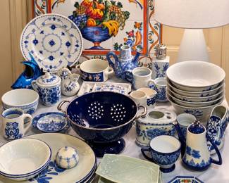 Blue-and-white lovers, this table is for you! A beautiful assortment of ceramic and porcelain pieces, including platters, bowls, teacups, pitchers, teapots, covered jars, serving dishes, decorative plates, a deep-blue colander, and more. Also featured are soft-green leaf plates, colorful tile artwork, and a modern white table lamp—perfect for collectors, entertaining, or home décor!