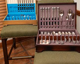 Two beautiful vintage silverplate flatware sets displayed in their original wooden storage chests. The collection includes dinner knives, forks, spoons, and assorted serving utensils featuring elegant decorative handles. Wonderful pieces for holiday entertaining, formal dining, collectors, or adding timeless charm to your table!
