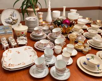 A china lover’s dream! Beautiful assortment of vintage teacups and saucers, floral plates, serving platters, bowls, milk-glass vases, decorative swans, miniature porcelain furniture, and elegant gold-trimmed pieces. Also featured are colorful decorative ornaments displayed in a striking amber centerpiece—perfect for collectors, entertaining, or adding vintage charm to your home!