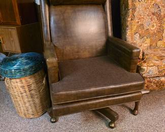 vintage high-back brown leather executive desk chair featuring a textured fabric seat cushion and a wooden swivel base with brass ball casters