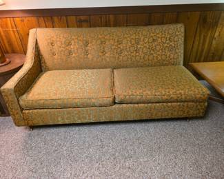 sectional vintage mid-century modern single-arm tufted sofa featuring a burnt orange and green floral brocade or damask pattern, left side sofa.