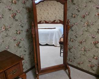 wood-finish cheval mirror with a decorative scrolled pediment top and swing-frame supports